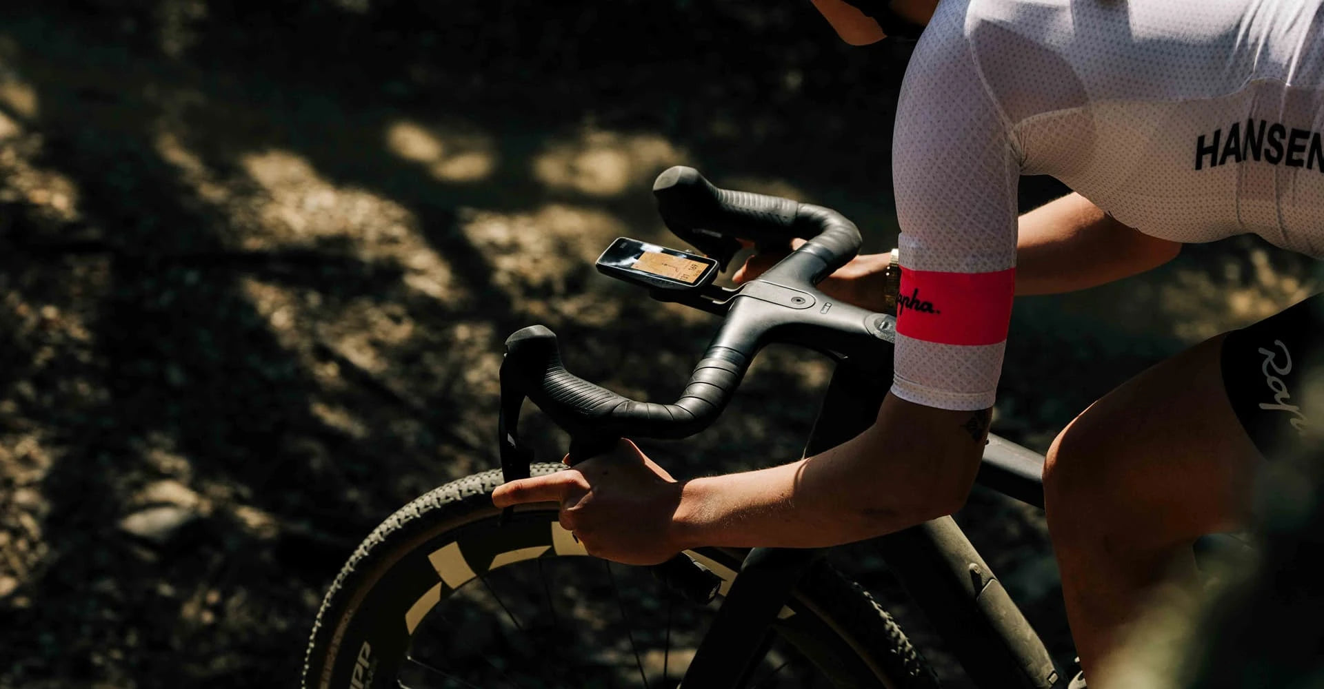 Person on a bicycle with a focus on the handlebar and gear shift, wearing a cycling outfit. Using Dura Bike Computer