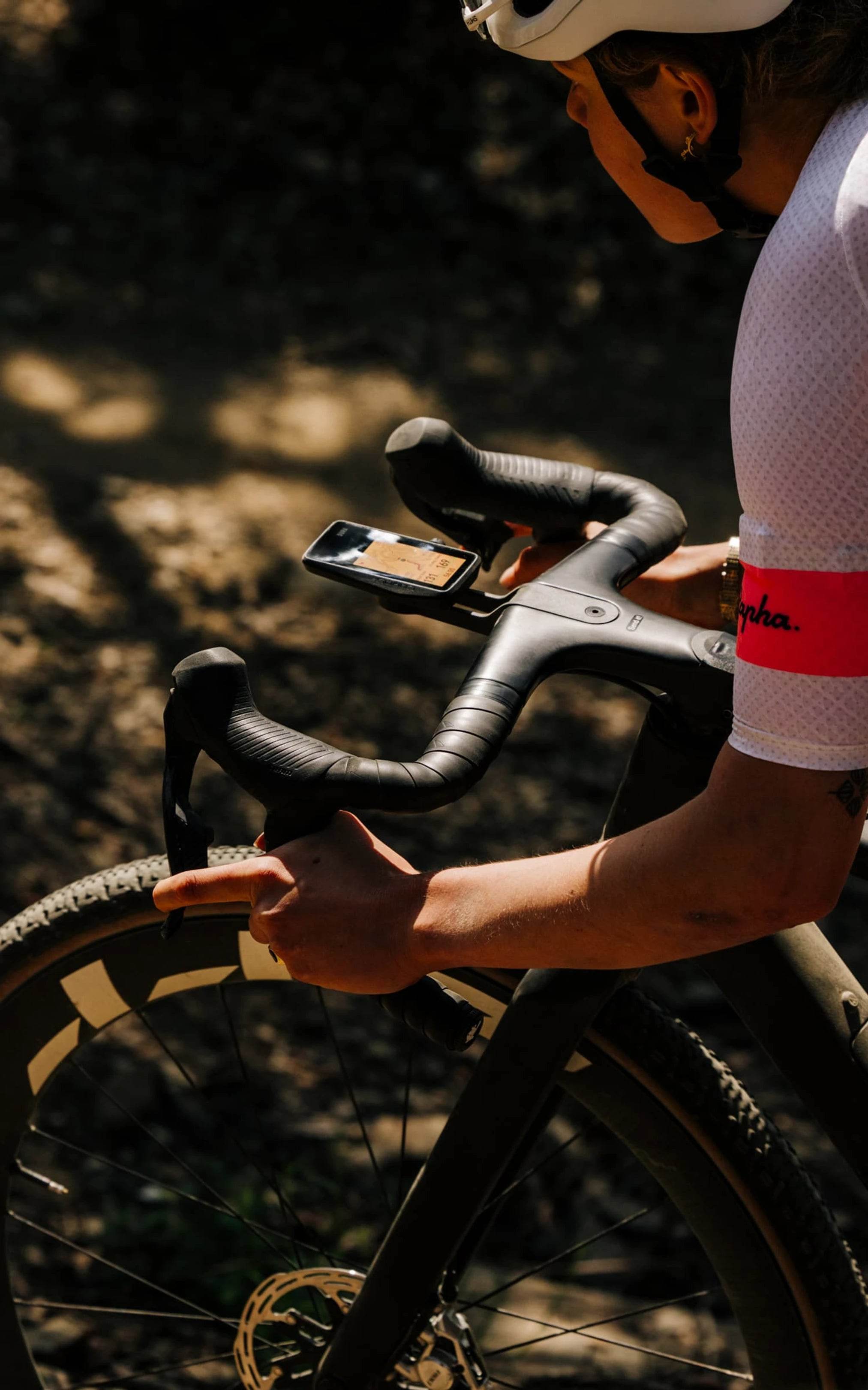 Person on a bicycle using a dura bike computer with a blurred natural background